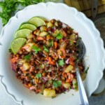 A bowl full of black chickpea, potatoes, vegetables and tamarind sauce.